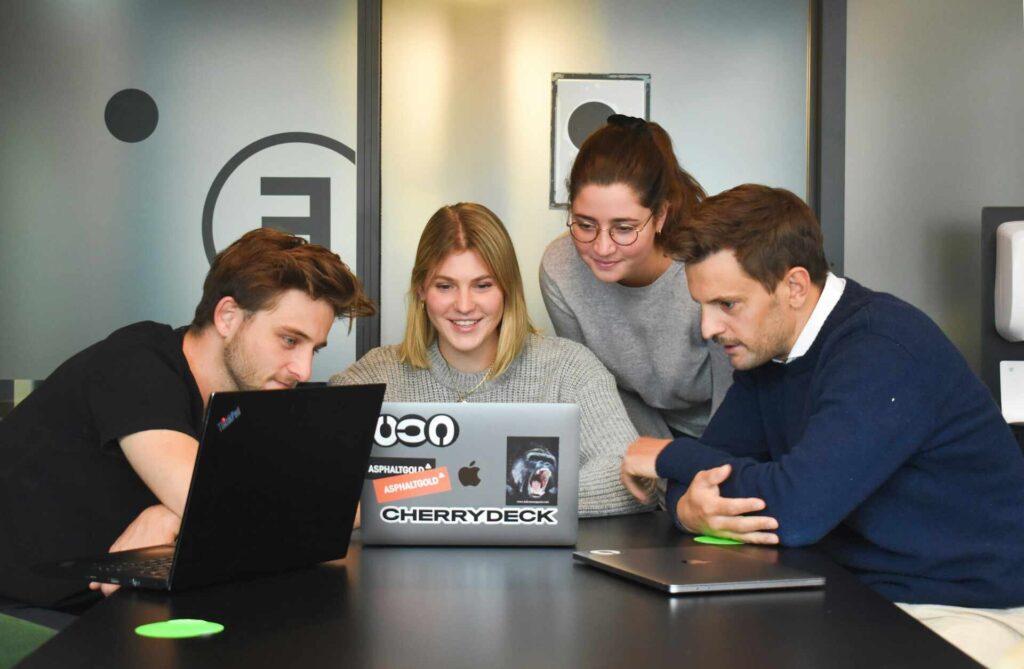 Group of developers gathered around a laptop, discussing and working together.